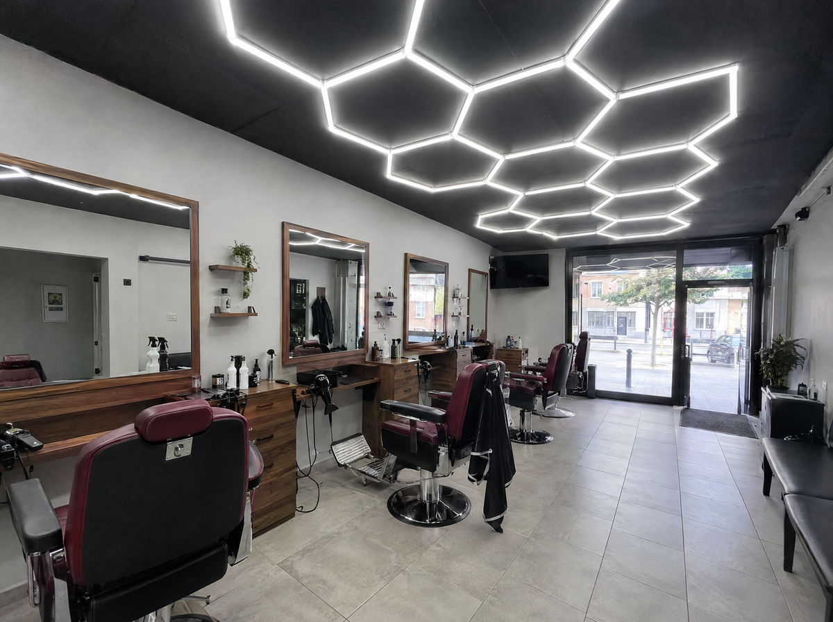 Neighbourhood barbershop concept with wood-look stations and geometric ceiling lighting